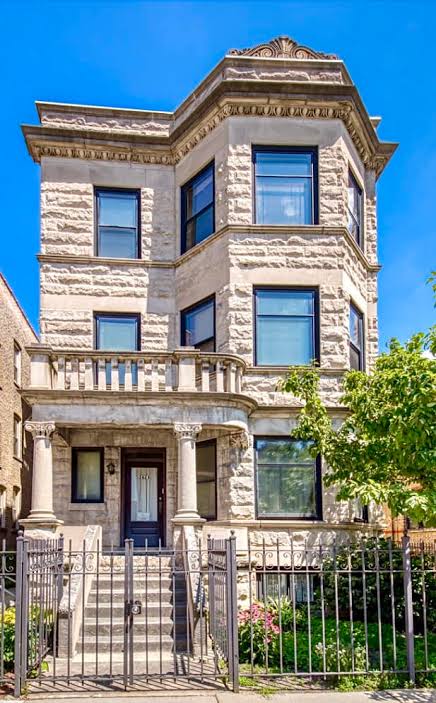 Chicago greystone three-flat: rusticated limestone facade with a three-sided bay, covered porch and carved cornice